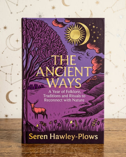 The Ancient Ways: A Year of Folklore, Traditions and Rituals to Reconnect with Nature book by Seren Hawley-Plows, standing upright on a wooden surface against a cream-colored background decorated with celestial patterns.